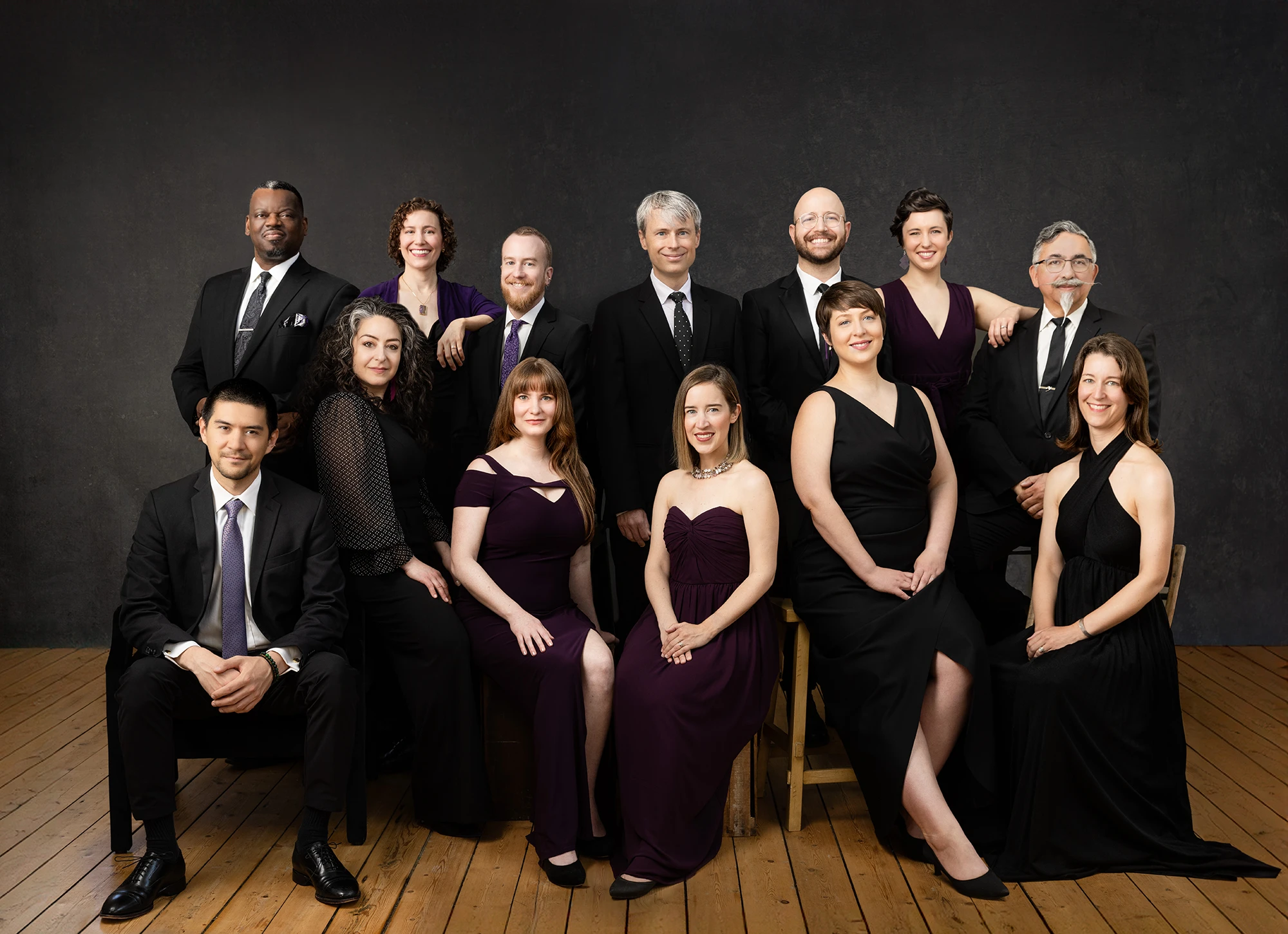 Skylark vocal ensemble sits calmly and slightly smiling looking at the camera.